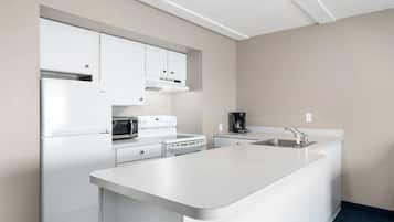 A modern kitchen with white cabinetry, a built-in oven, a microwave, and a coffee maker.