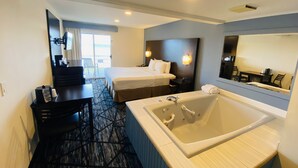 Habitación de hotel con una cama grande, un dormitorio independiente, un baño con bañera, un escritorio y una silla.