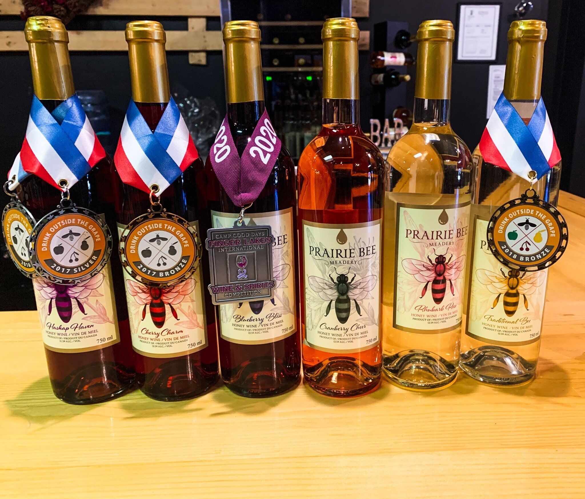 A row of wine bottles with medals on top, each labeled with a different brand and type of wine.
