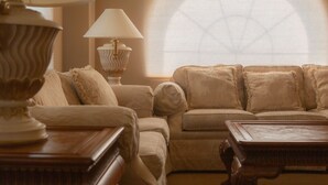 A room with a sofa, two lamps, and a window with a view. - Grant Hall Hotel (Moose Jaw)