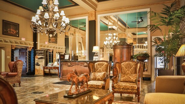 A luxurious lobby with ornate furniture, chandeliers, and a large mirror reflecting the space. - Grant Hall Hotel (Moose Jaw)