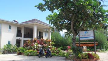 A building with a sign reading "MOANA SANDS" and two parked motorcycles in front.
