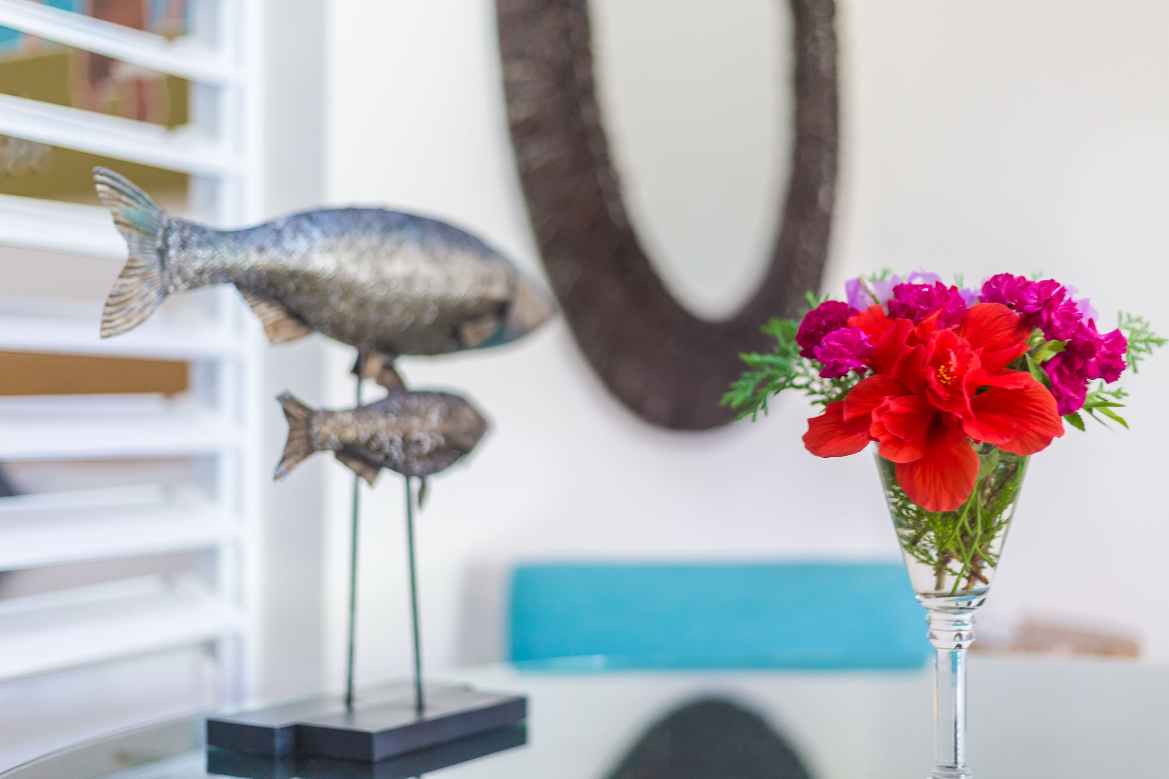 A fish sculpture on a table with a vase of flowers.