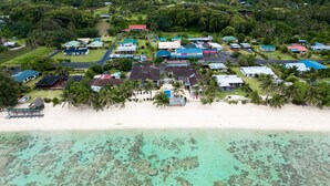 An aerial view of a coastal resort with multiple buildings, a beach, and clear turquoise waters. - Moana Sands Villas & Apartments (Rarotonga)