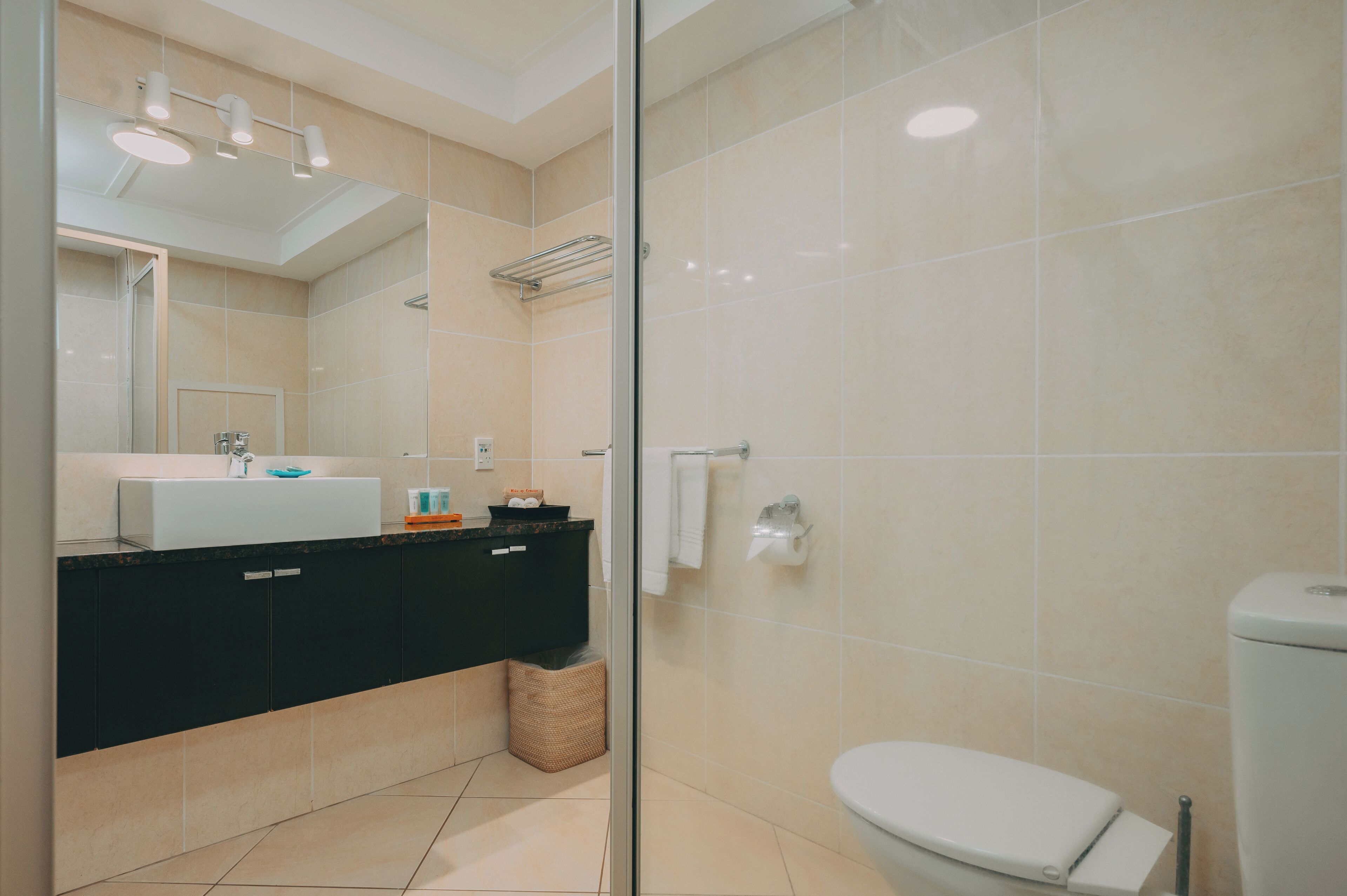 Un baño moderno con cabina de ducha de vidrio, inodoro blanco y tocador negro con lavamanos.