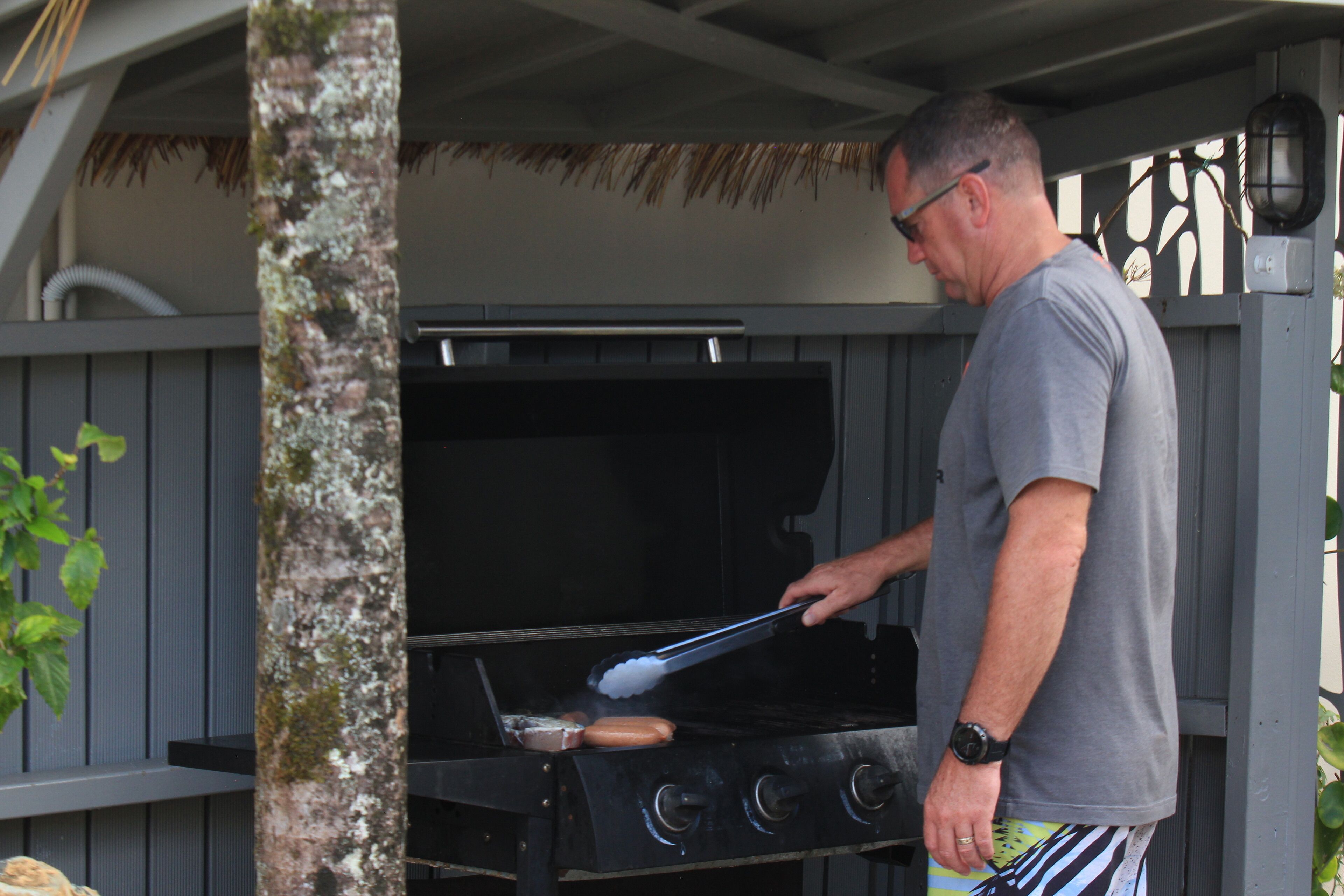 Un hombre asando al aire libre con una barbacoa.