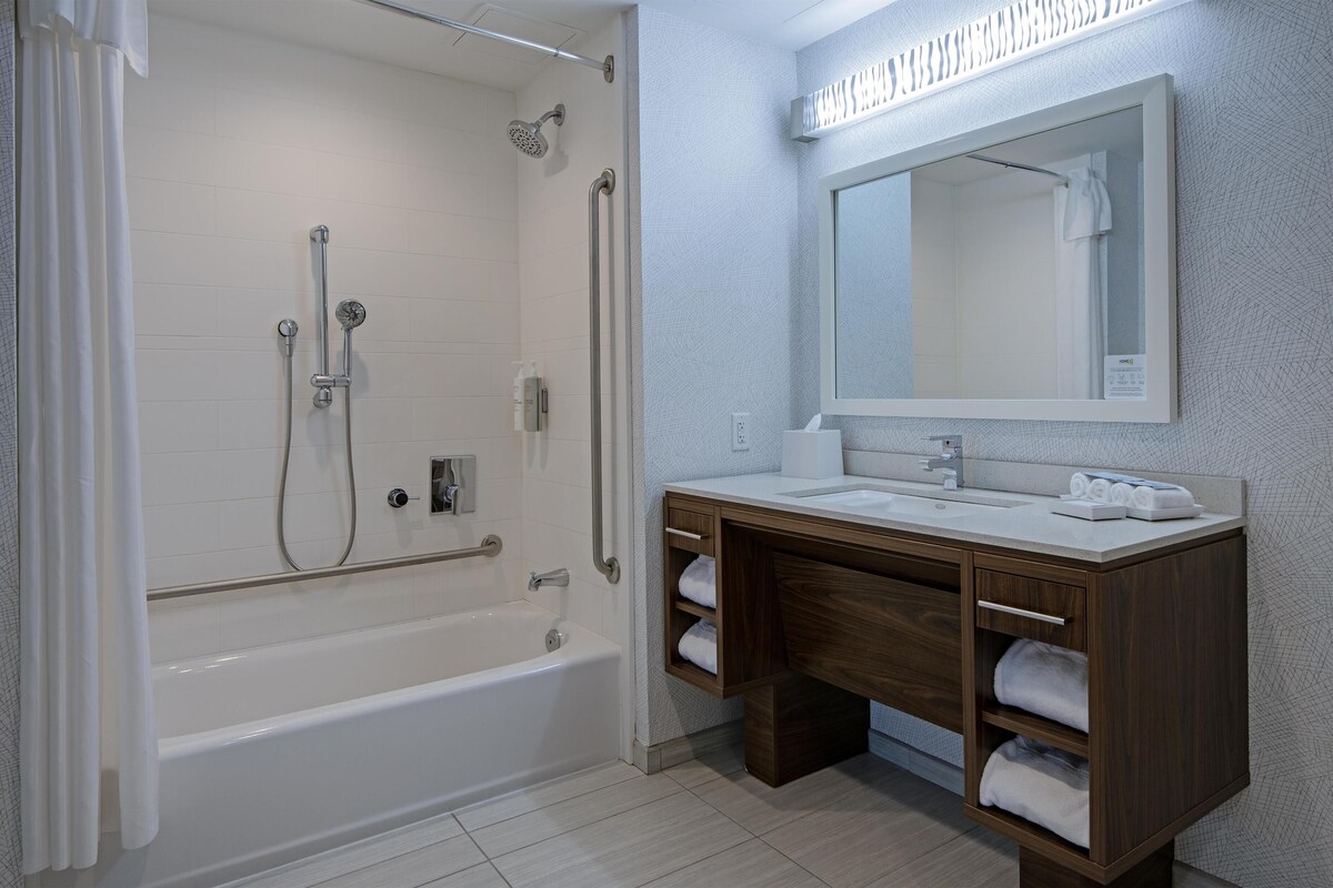 Un baño moderno con bañera, ducha, tocador con espejo y estantes empotrados.