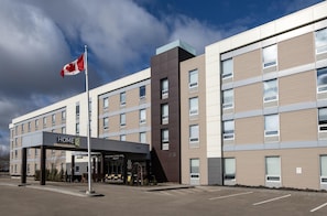 A multi-story hotel with a clear sky and a Canadian flag. The building has a modern design with a mix of window styles. - Home2 Suites by Hilton West Edmonton, Alberta, Canada (Edmonton)