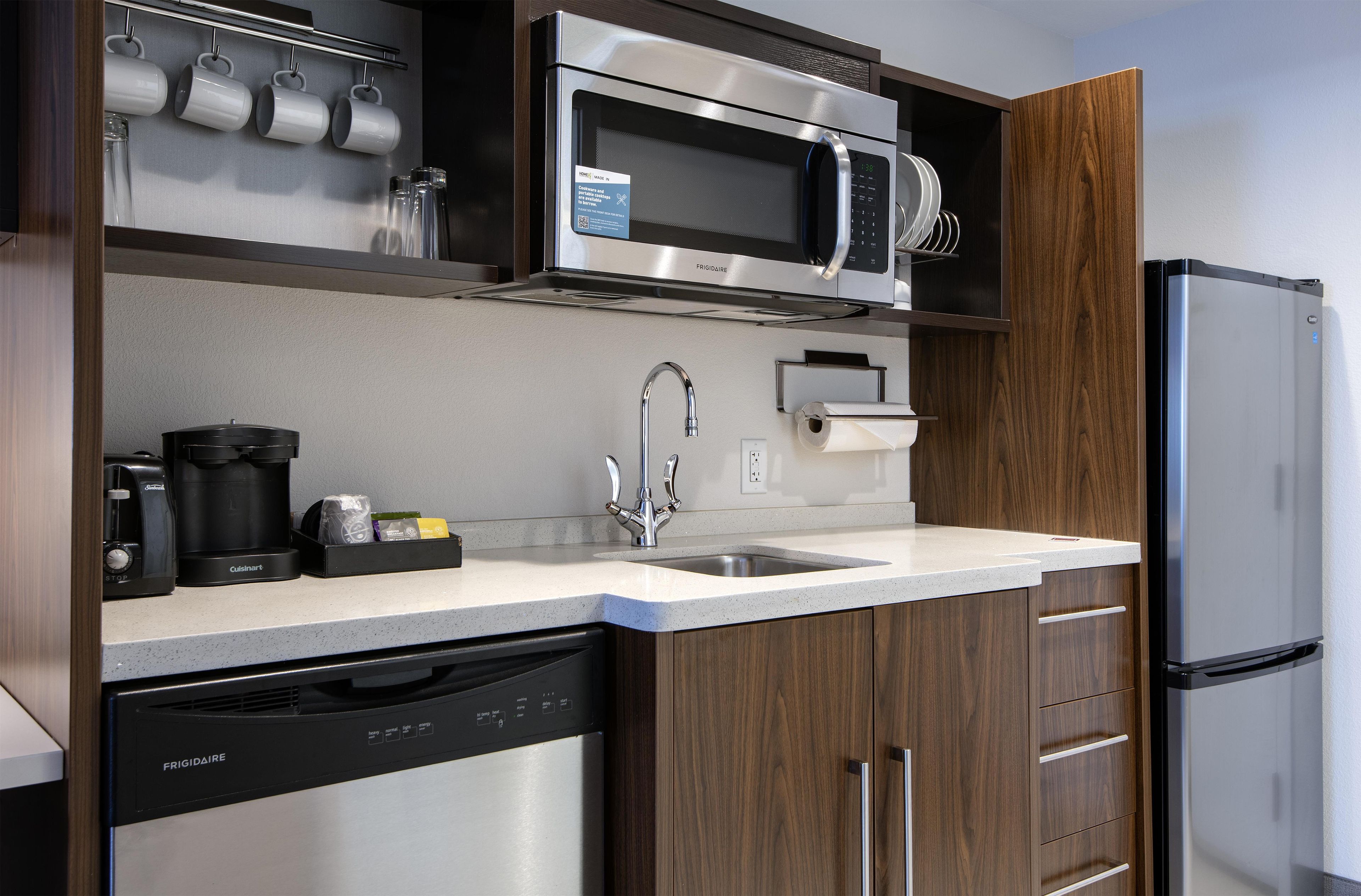 A kitchen with a stainless steel microwave, coffee maker, dishwasher, and a refrigerator.