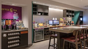 A coffee shop with a counter, bar stools, and a refrigerator.