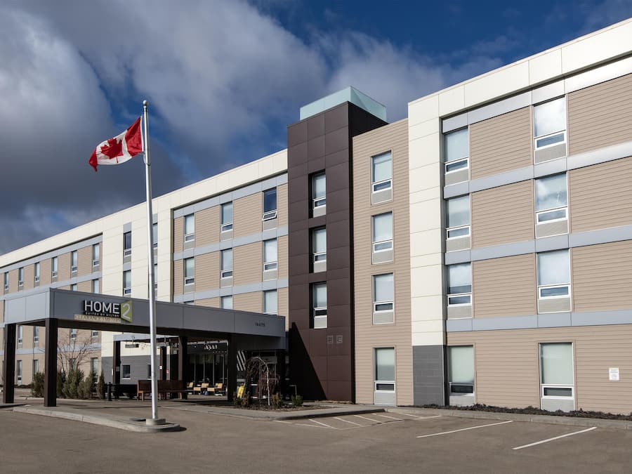 A multi-story hotel with a clear sky and a Canadian flag. The building has a modern design with a mix of window styles.