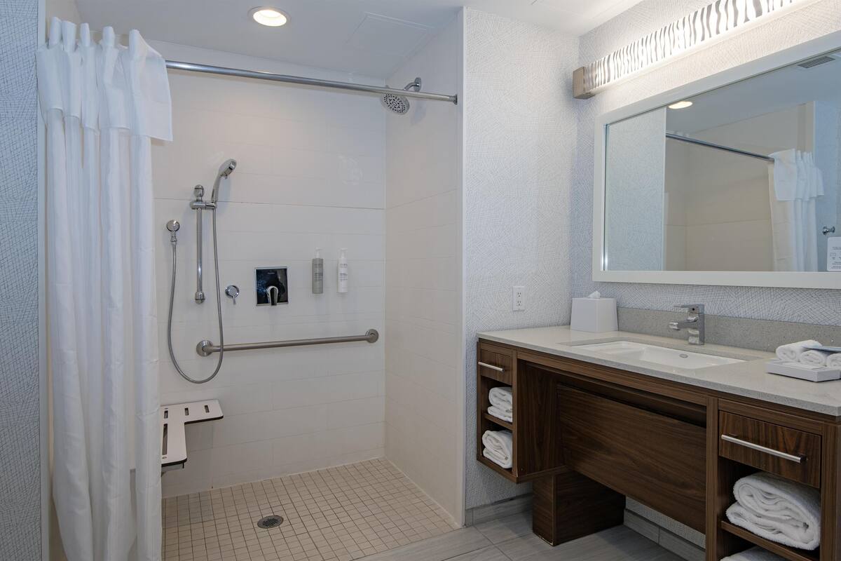 A modern bathroom with a walk-in shower, a vanity with a mirror, and a towel rack.