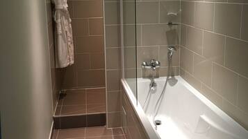 A modern bathroom with a glass-enclosed shower, a white bathtub, and a towel rack with a bathrobe.