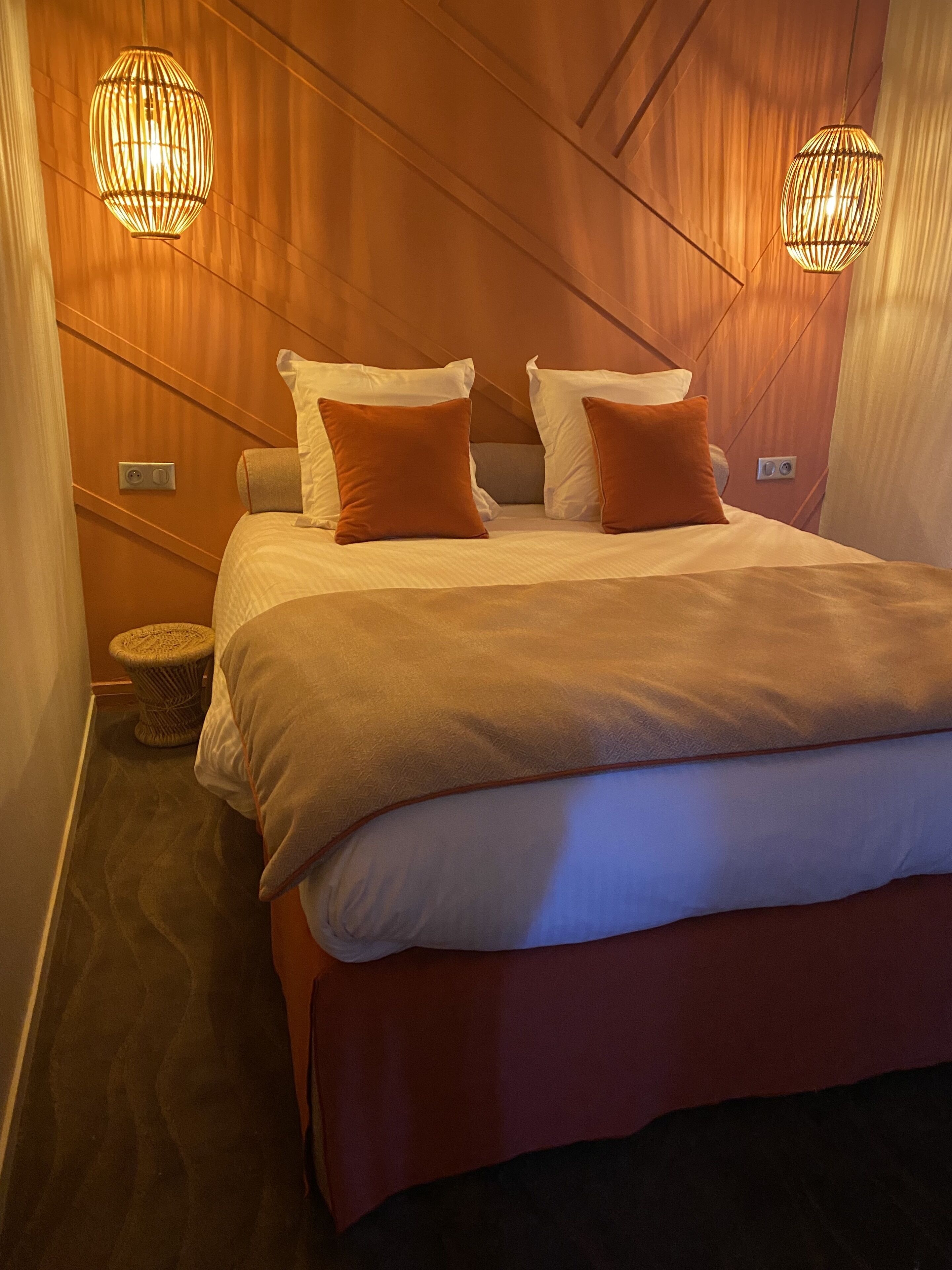 Una habitación de hotel con una cama grande, dos almohadas, una mesita de noche y dos lámparas de pared.