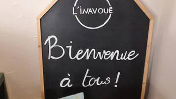 A blackboard with the text "Bienvenue à tous!" and a logo above it. Below the blackboard, there are two books on a wooden stand.