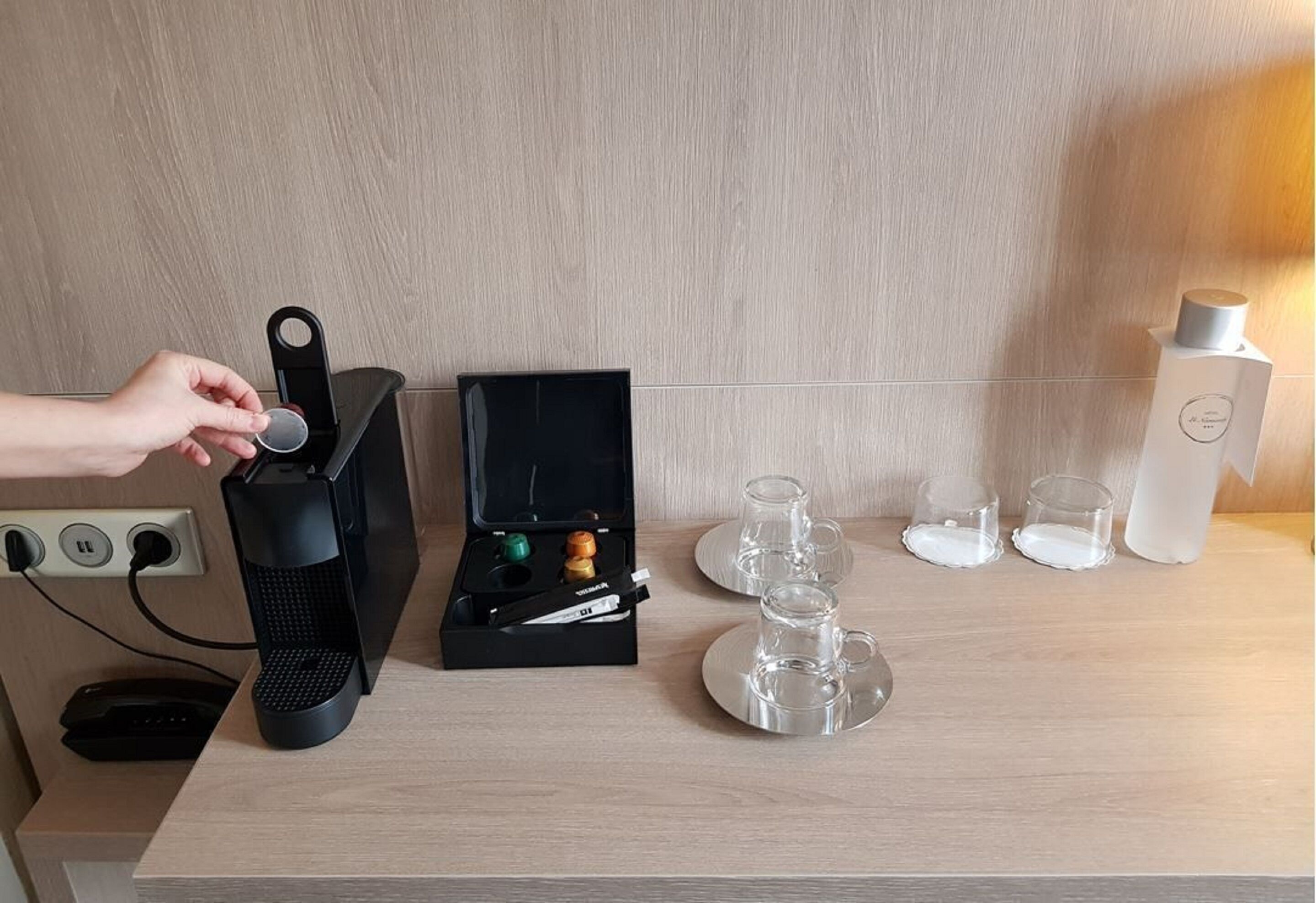 A coffee machine, a tea set, and two cups on a wooden table.