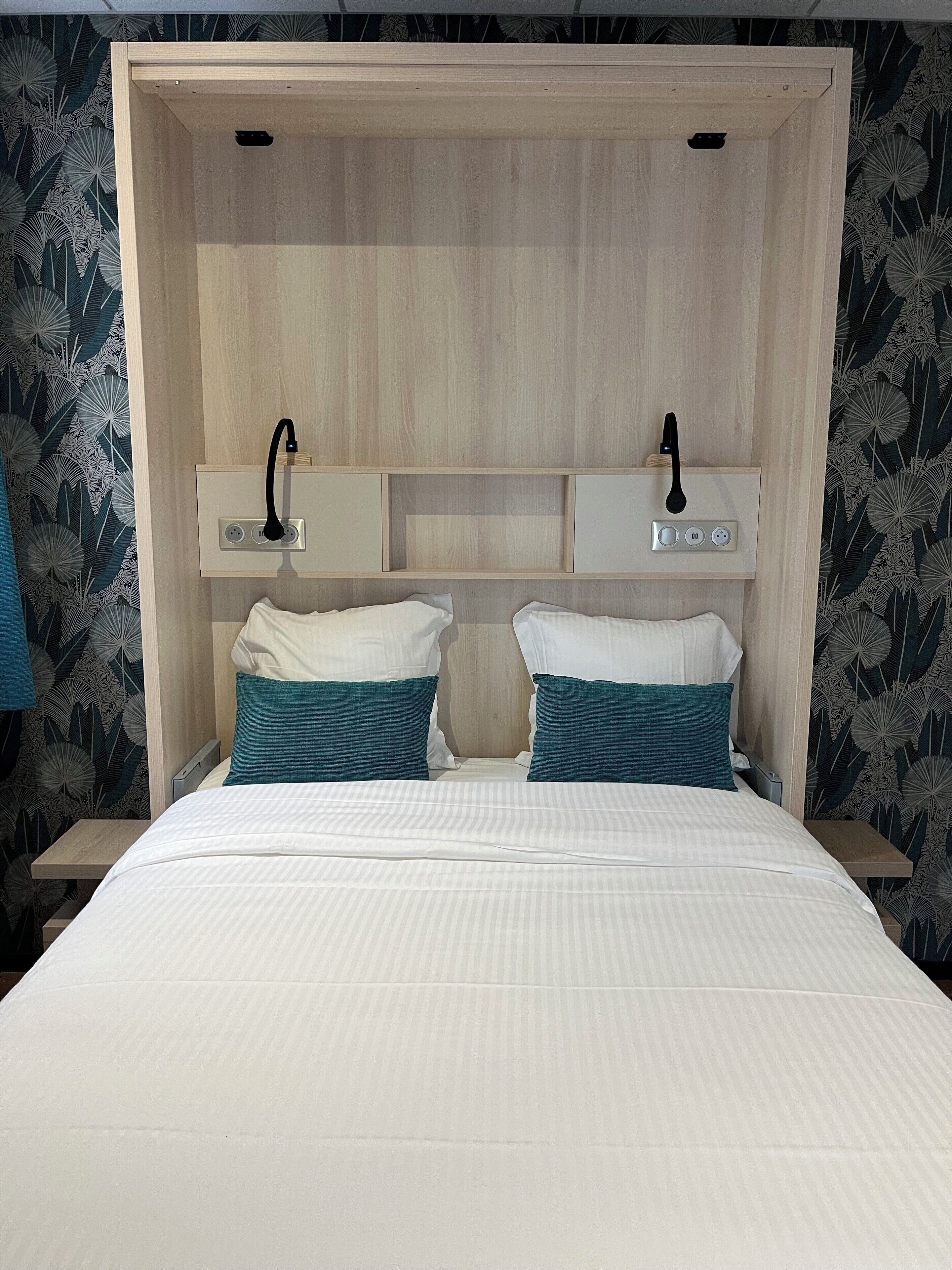 A double bed with a wooden headboard, two bedside tables, and a built-in shelf with a lamp.