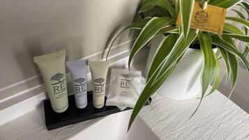 A bathroom shelf with three bottles of Rê brand skincare products and a small packet of soap.