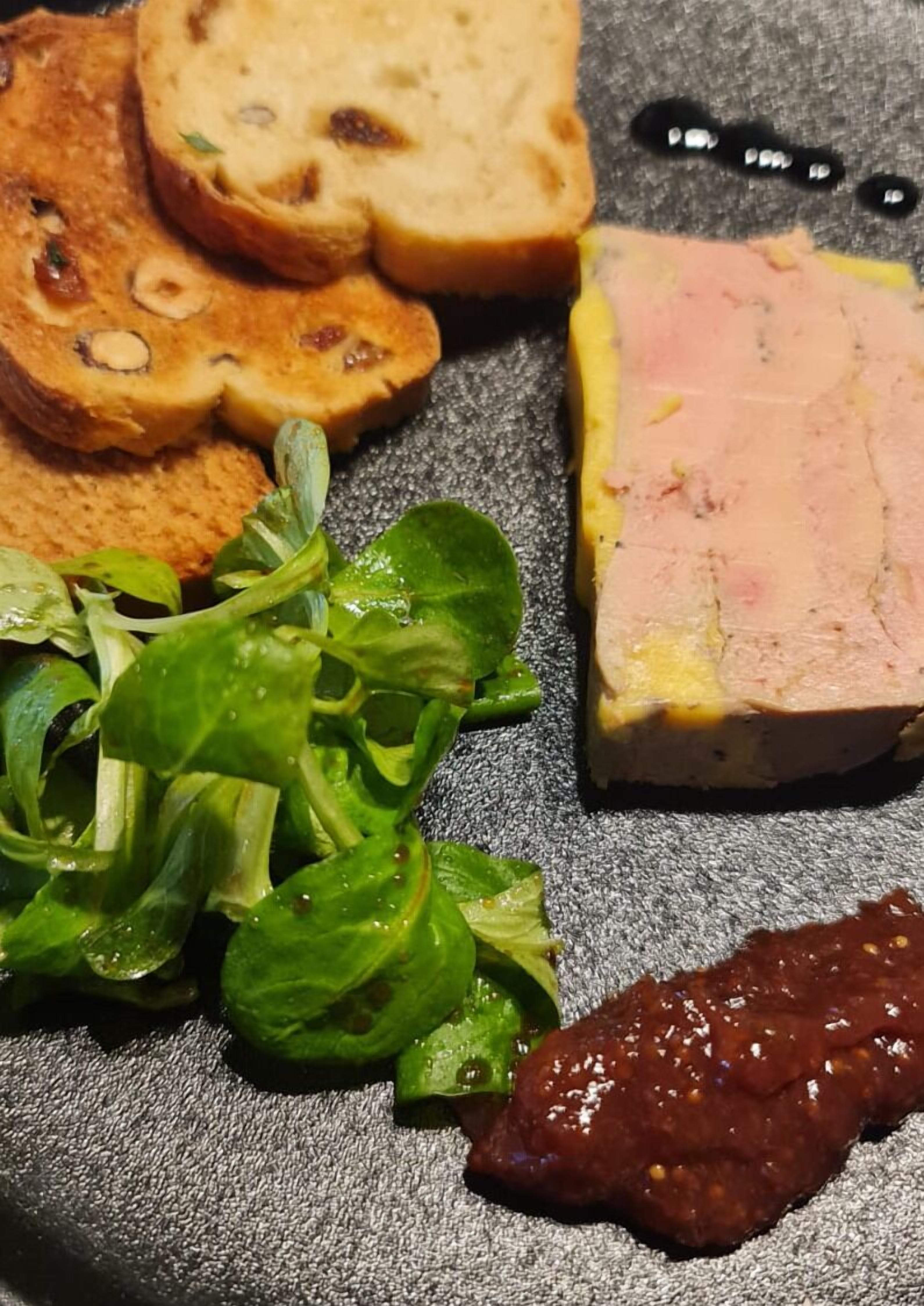 A plate with slices of bread, a piece of meat, and a green salad.