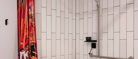 Zona de ducha con pared de azulejos blancos, cabezal de ducha y perchero.