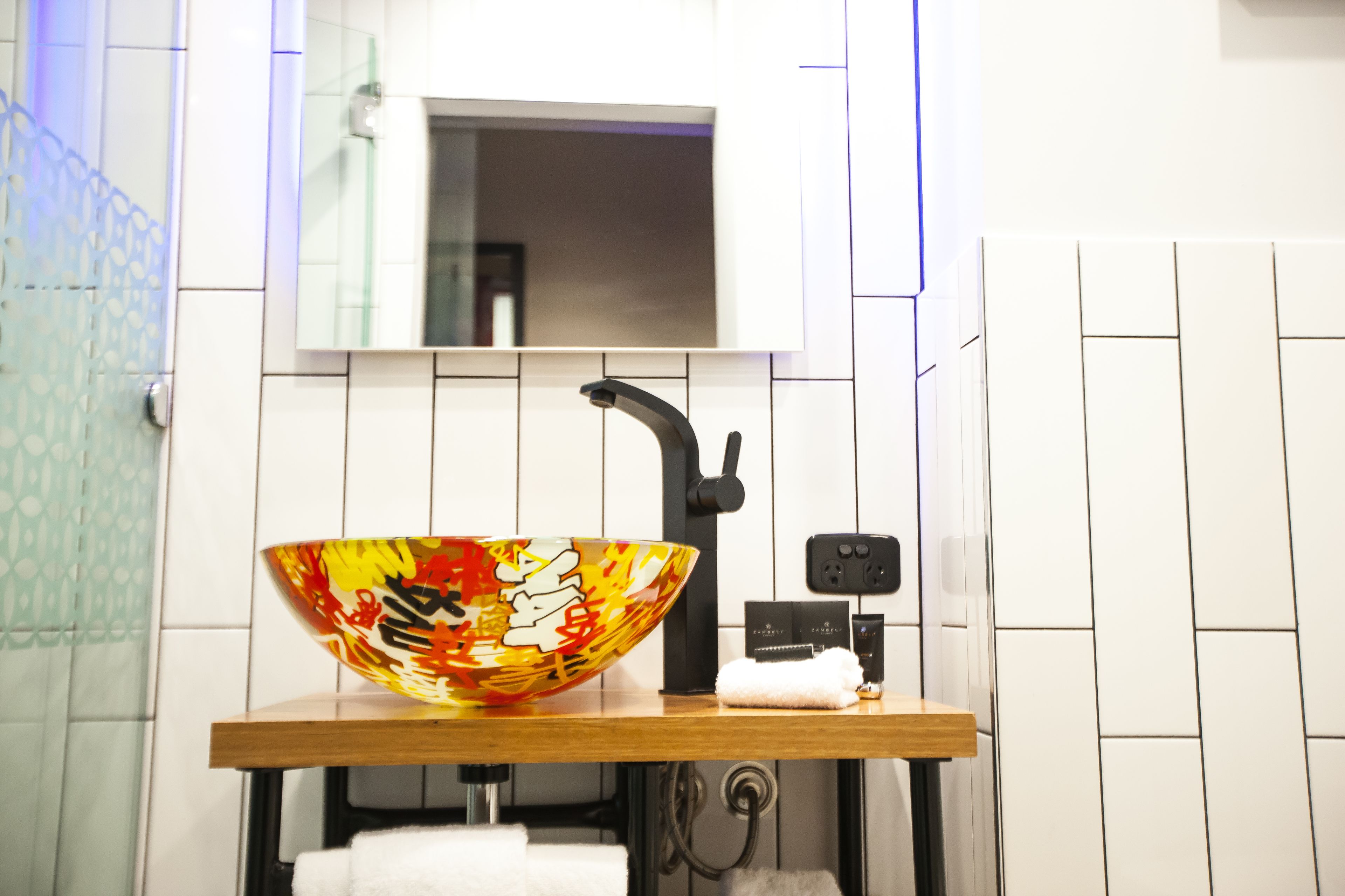 Un baño moderno con un lavamanos decorativo de gran tamaño, un espejo y un perchero para toallas.