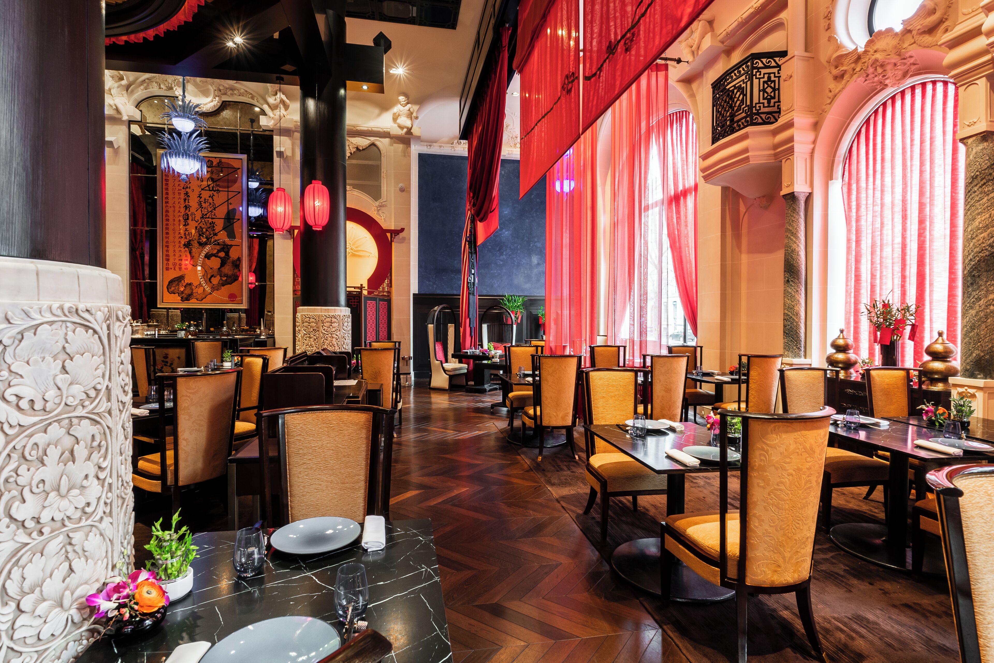 Un restaurante con varias mesas y sillas, decoraciones ornamentales en las paredes y un candelabro.