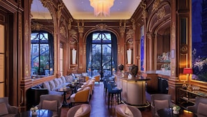 A luxurious interior with ornate wood paneling, a grand chandelier, and a bar area with seating. - The Peninsula Paris (Paris)