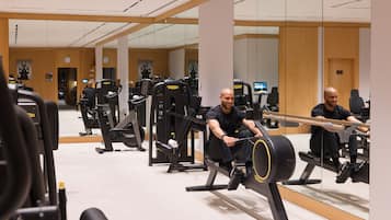 Ein Fitnessstudio mit Rudergeräten, Spiegeln und Trainingsgeräten.