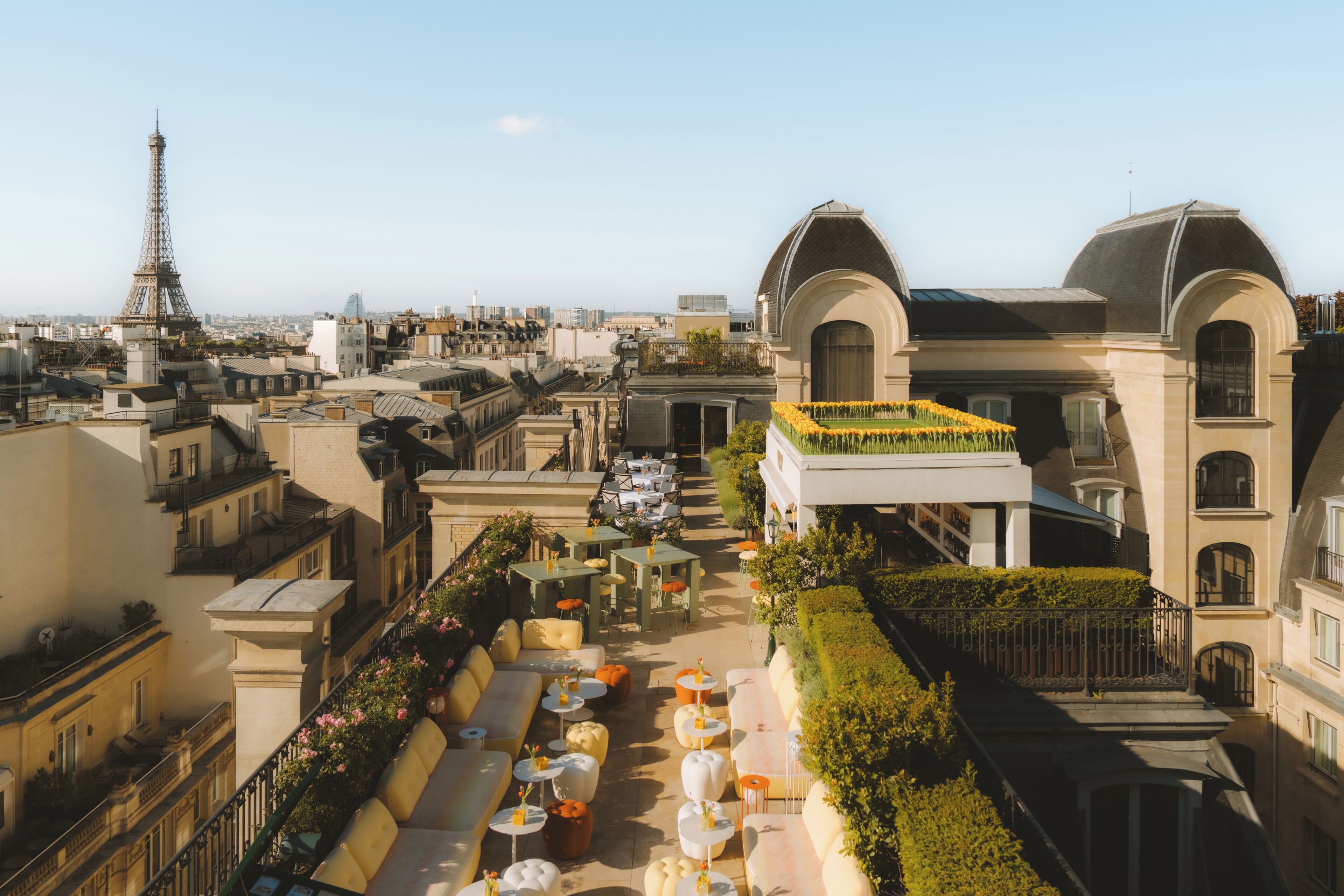 A rooftop terrace with outdoor seating, a view of the Eiffel Tower, and classic European architecture.