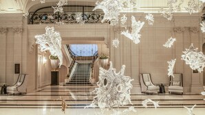 En imponerende lobby med trappe, overdådige lysekroner og klassisk arkitektur.