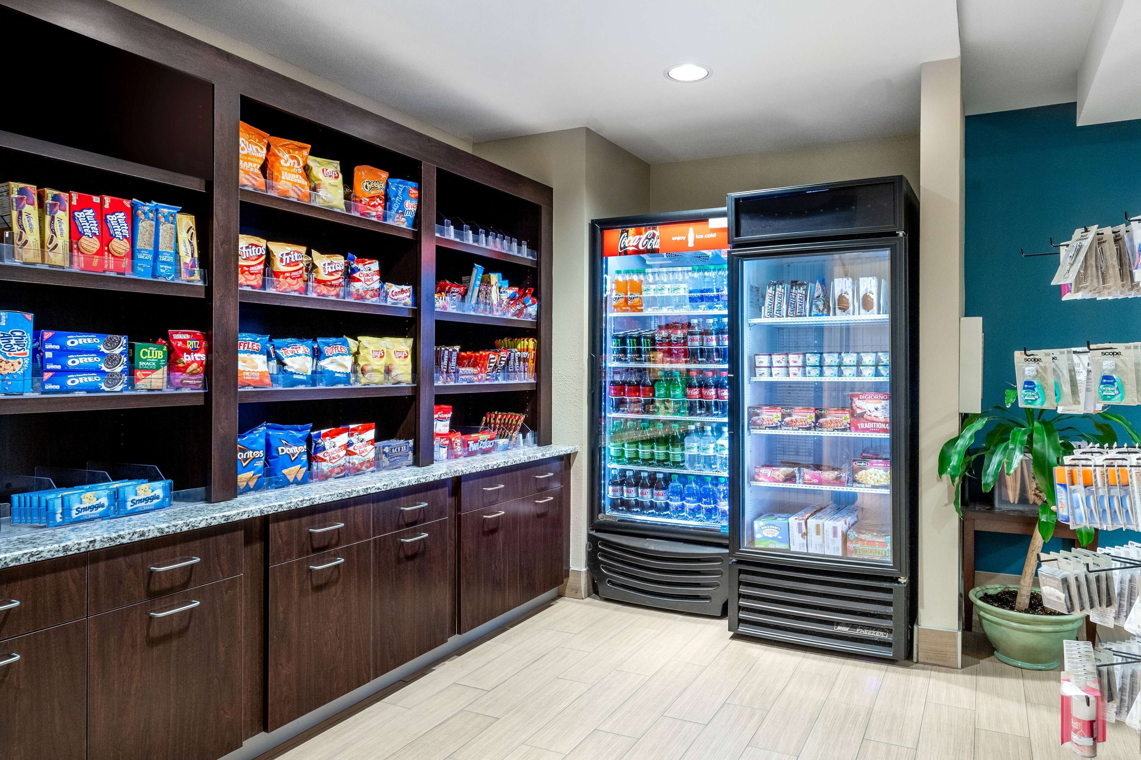A snack and beverage area with shelves stocked with chips, cookies, and a Coca-Cola refrigerator.