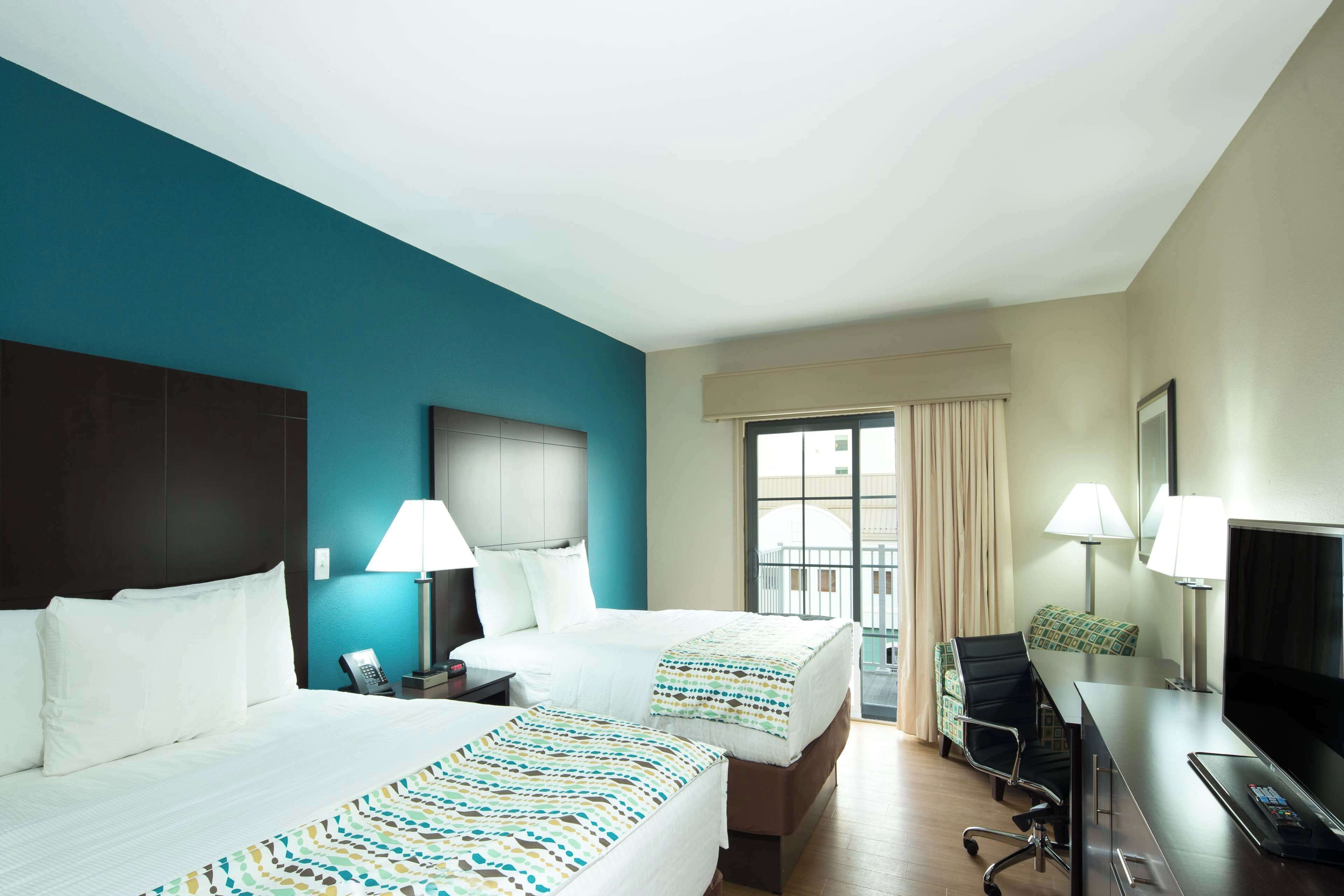 A hotel room with two beds, a desk with a TV, and a chair.