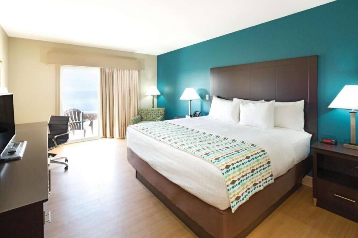 Une chambre d’hôtel avec un grand lit, un bureau, une chaise et une vue sur la ville.
