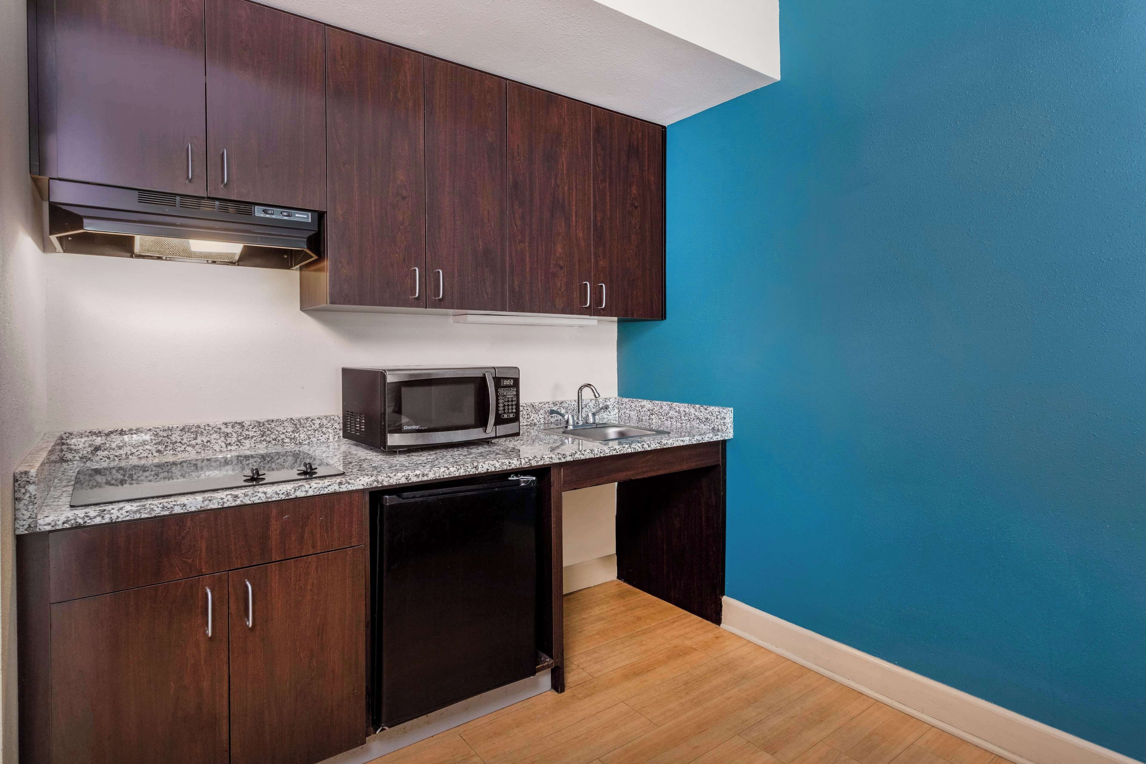 A kitchen with dark wooden cabinets, a microwave, a sink, and a dishwasher.