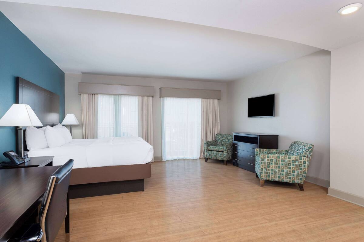 Une chambre d’hôtel comprenant un lit, deux chaises, un bureau avec une lampe, une télévision et un téléphone.