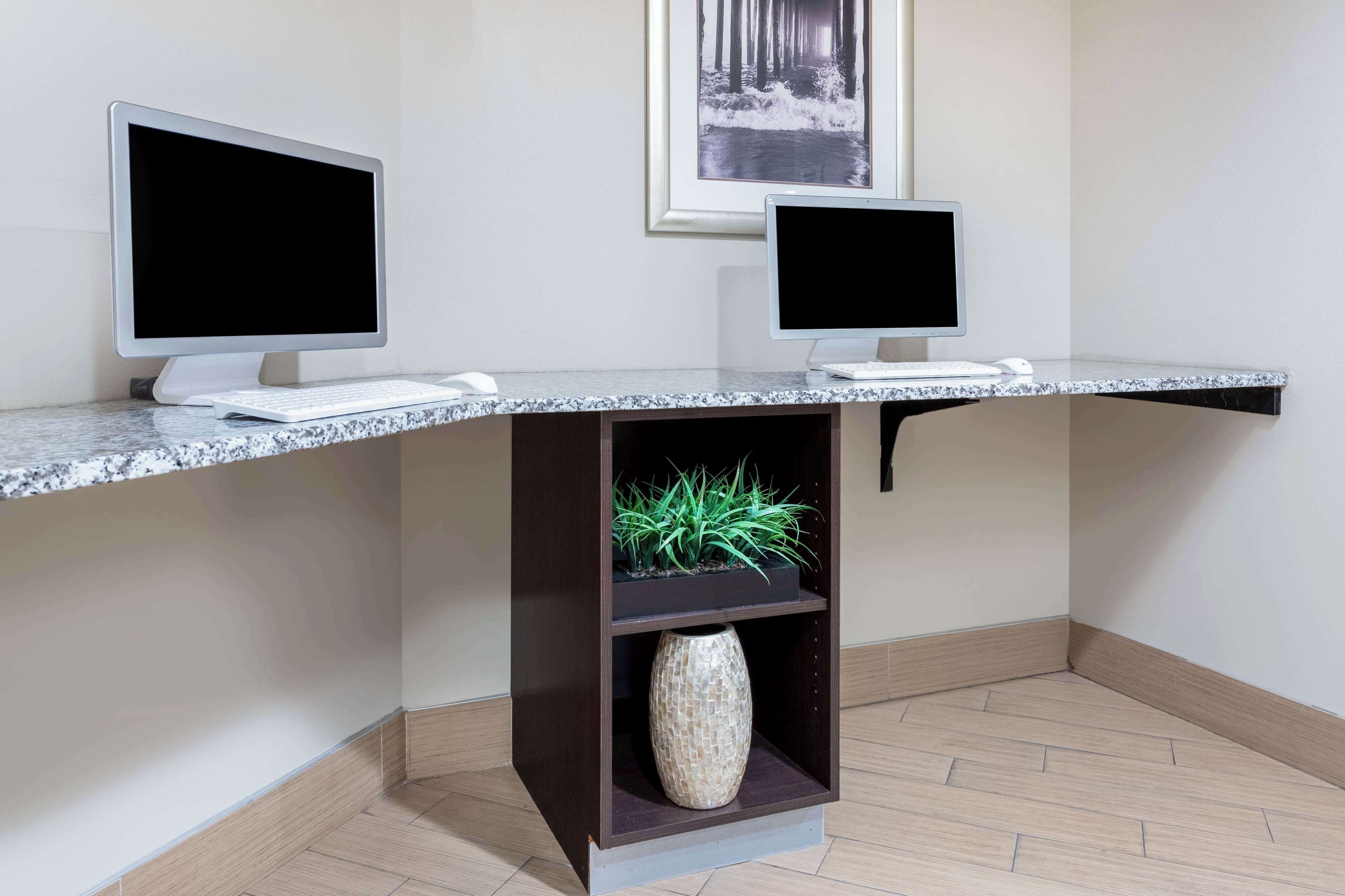 Una reception con due monitor, una tastiera e un vaso di fiori.