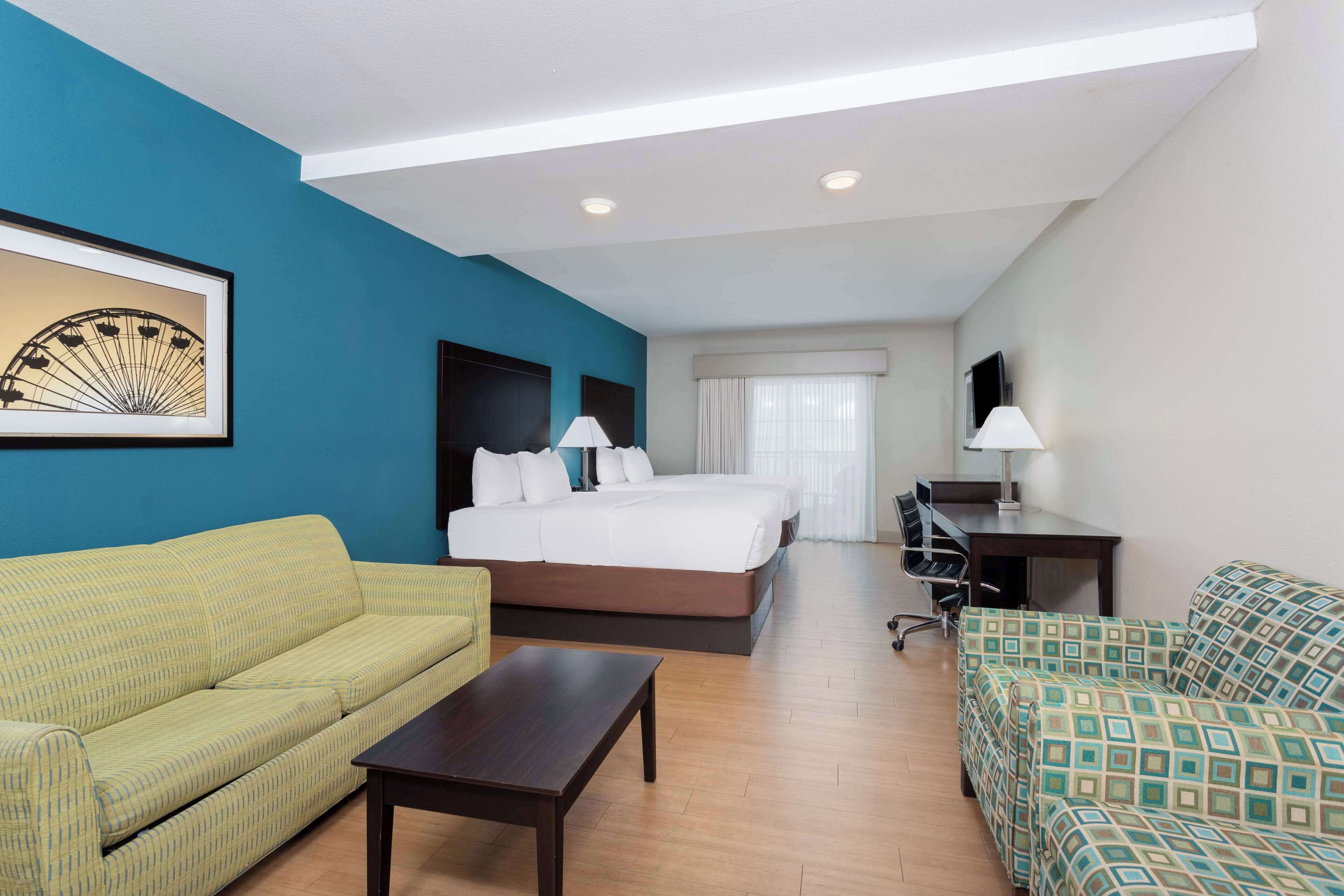A hotel room with a bed, a desk, a sofa, and a coffee table.