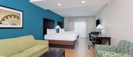 A hotel room with a bed, a desk, a sofa, and a coffee table.