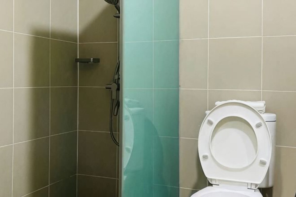 A bathroom with a shower, toilet, and a glass partition.
