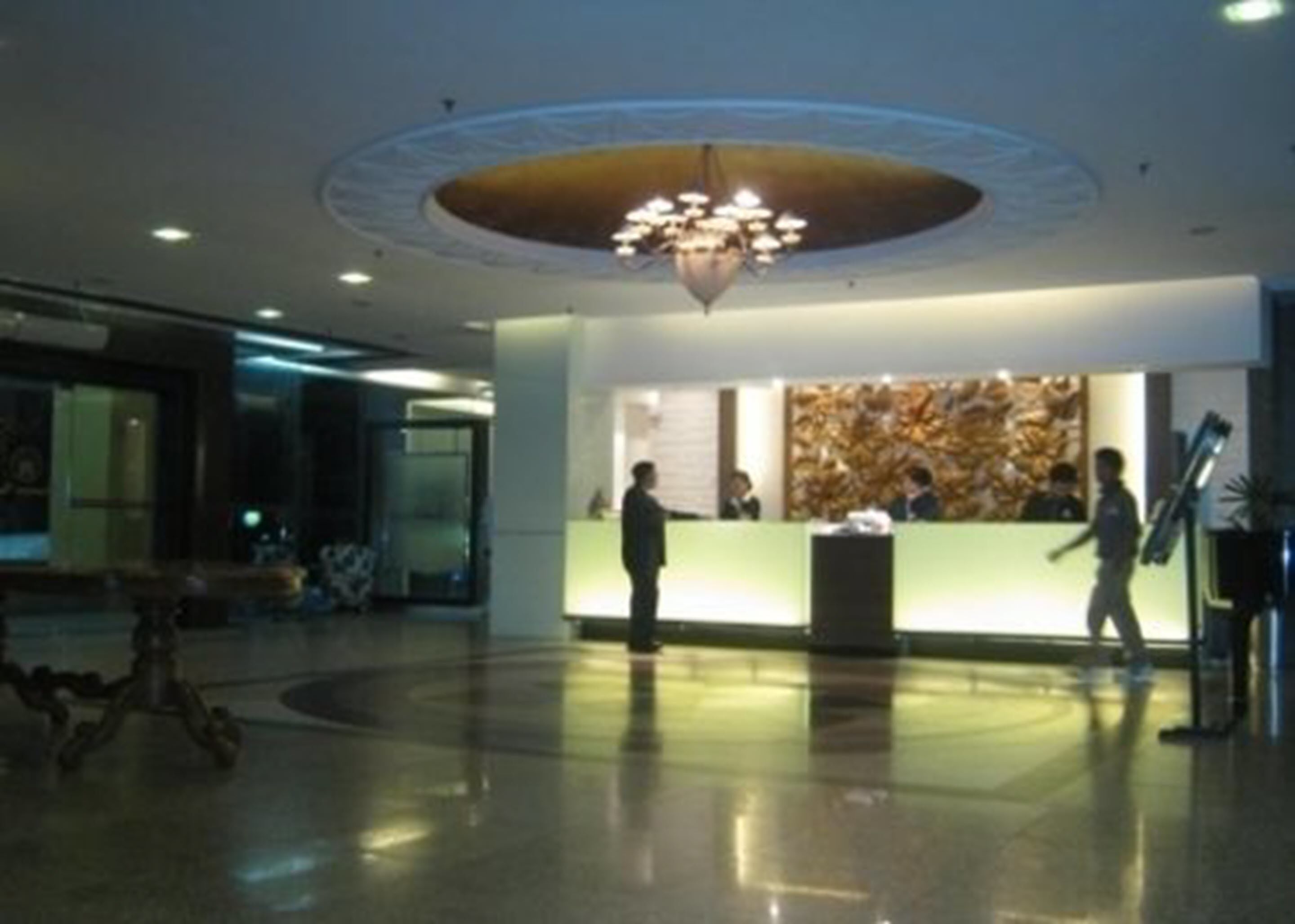 A lobby with a reception desk, a chandelier, and a large abstract wall art piece.