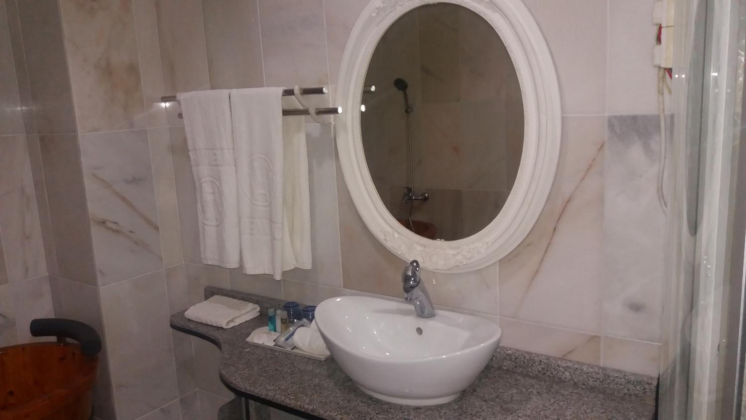 A bathroom with a white sink, a round mirror, and a shower.