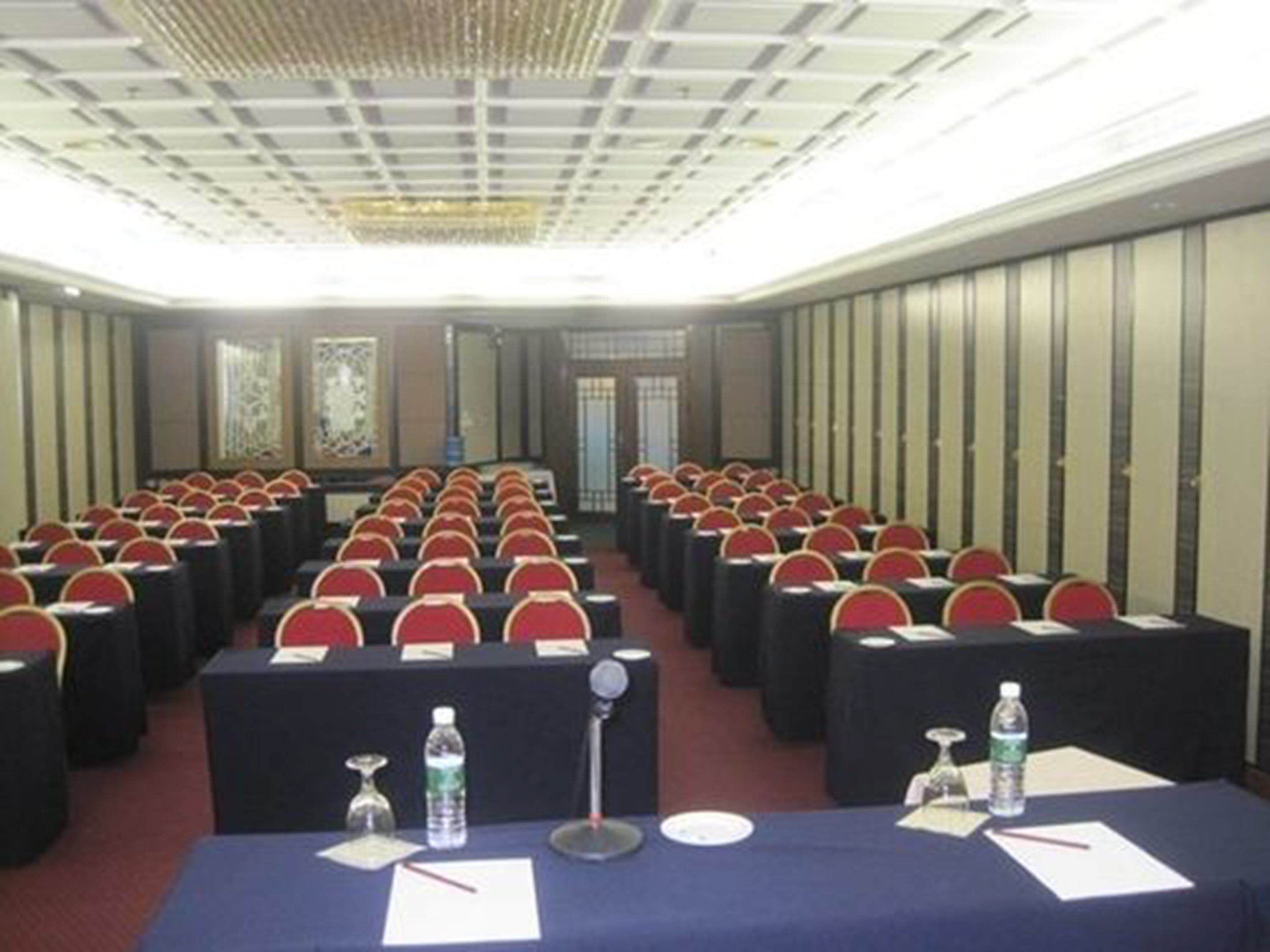 A conference room with rows of tables, chairs, and a podium.