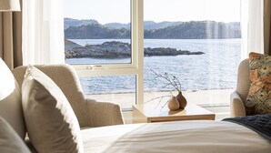 Habitación de hotel con un ventanal amplio que ofrece vistas de un paisaje costero.