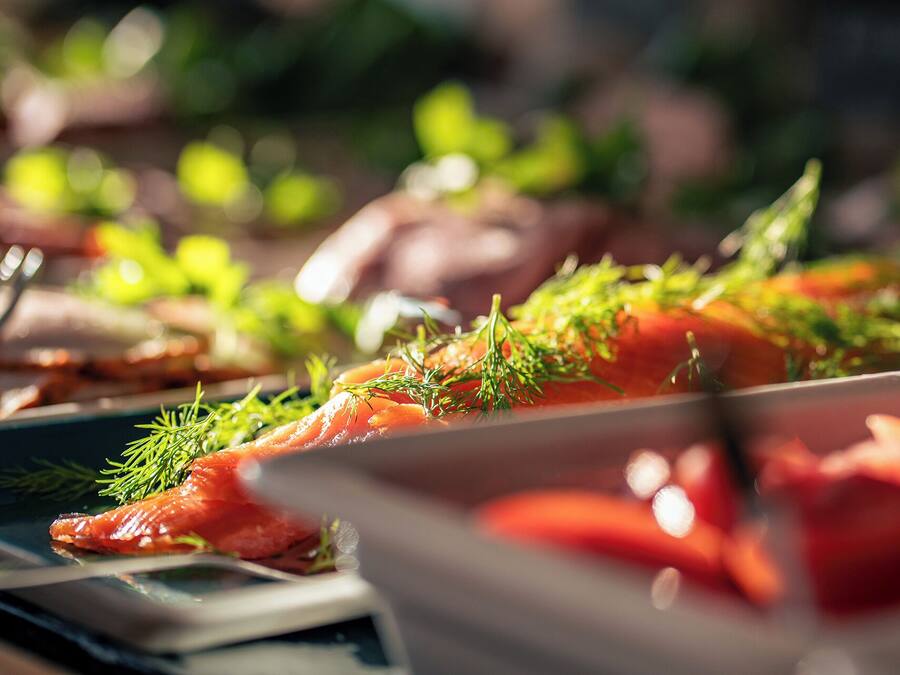 Une table dressée avec différents plats, dont du saumon garni d’herbes.