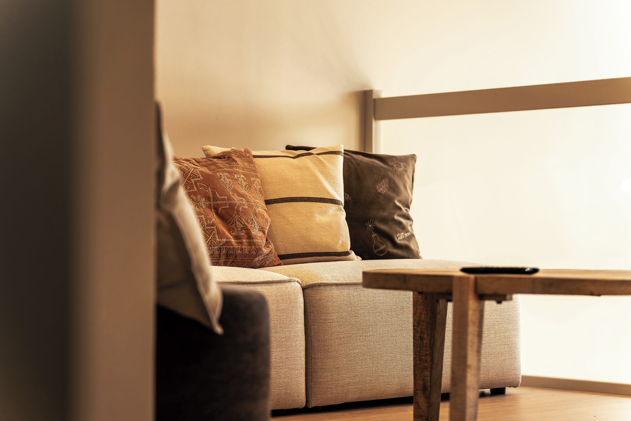 Una esquina de habitación con un sofá, una mesa y un ventanal.
