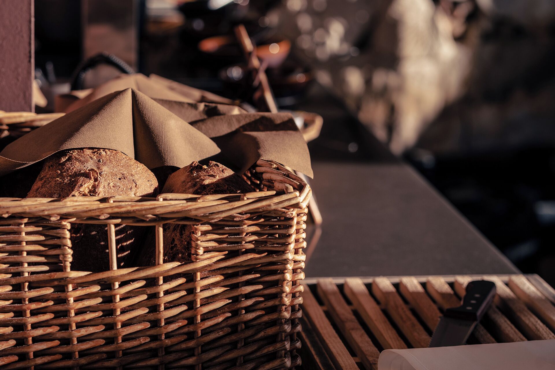 A wicker basket filled with bread and baguettes on a wooden table.