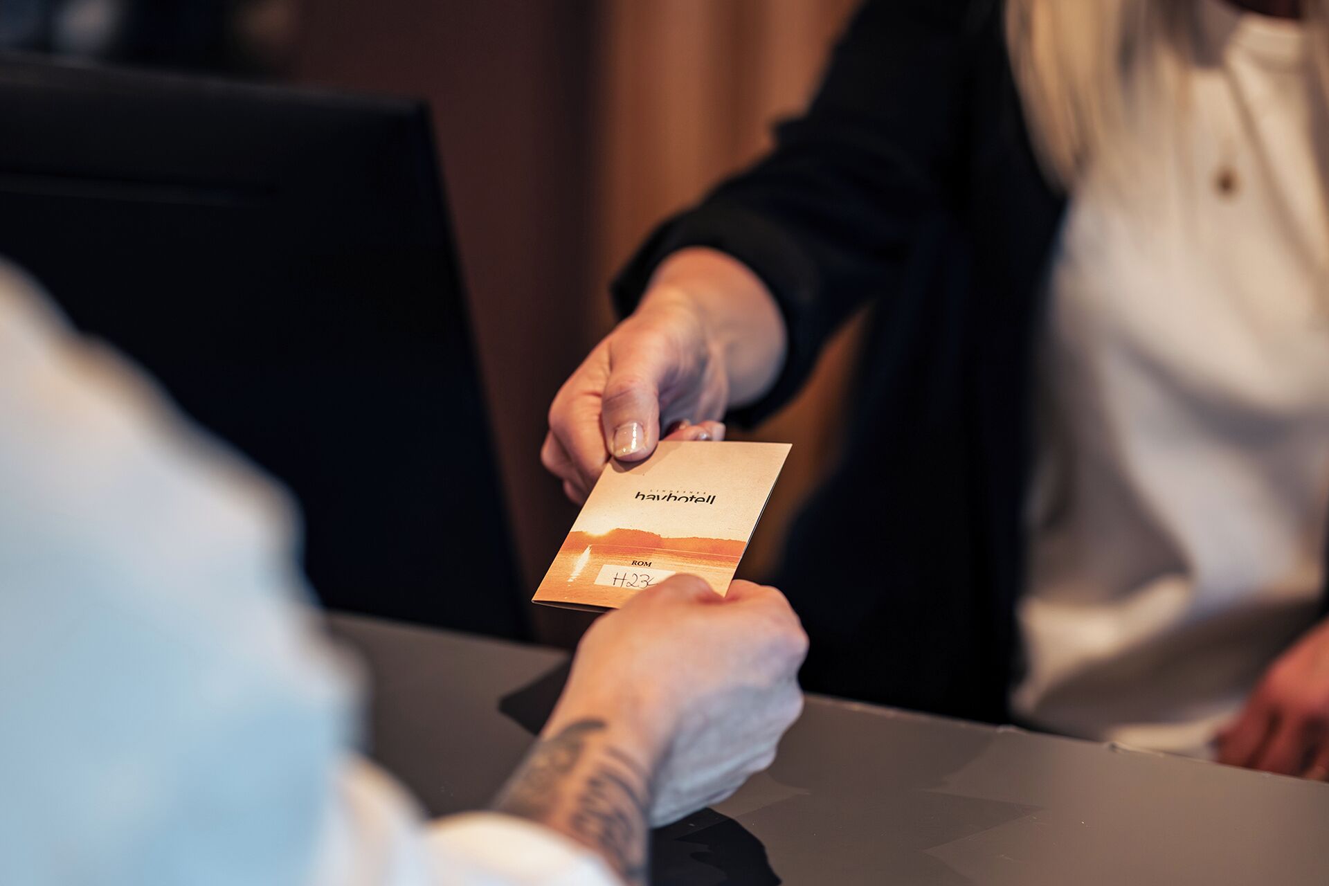 A person handing over a card to another person at a table.