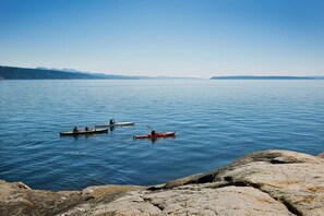 A calm lake with three kayaks on the water, surrounded by rocky shores.