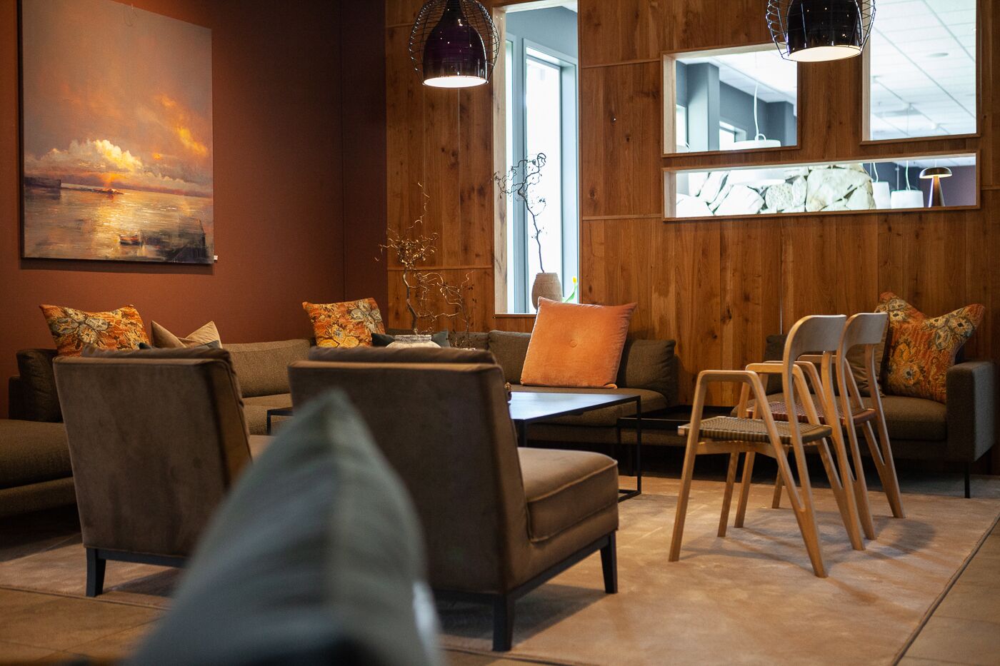 Una sala de estar moderna con pared de madera, un sofá, sillones, una mesa de centro y un comedor con sillas.
