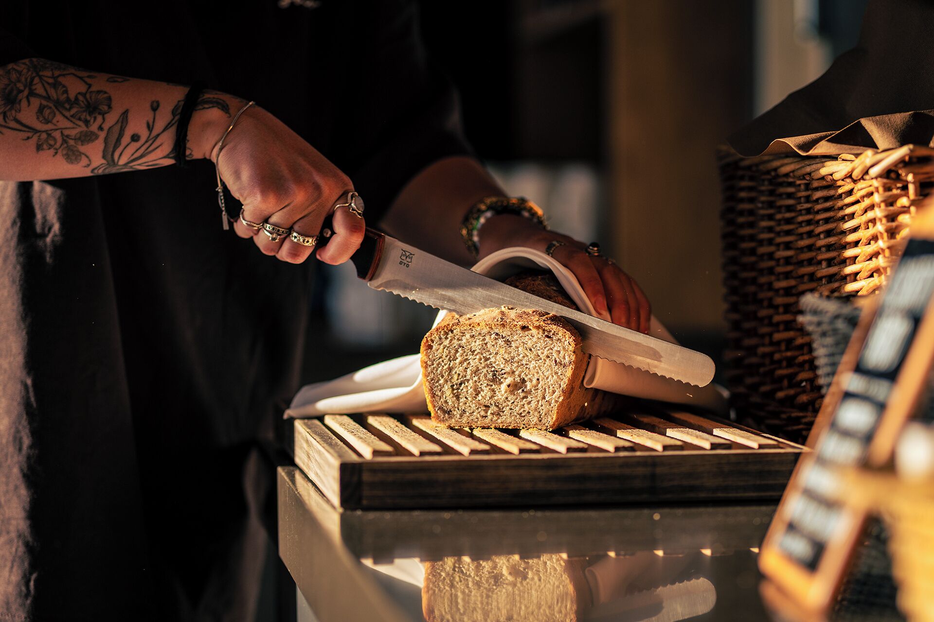 A person cutting bread on a wooden cutting board.